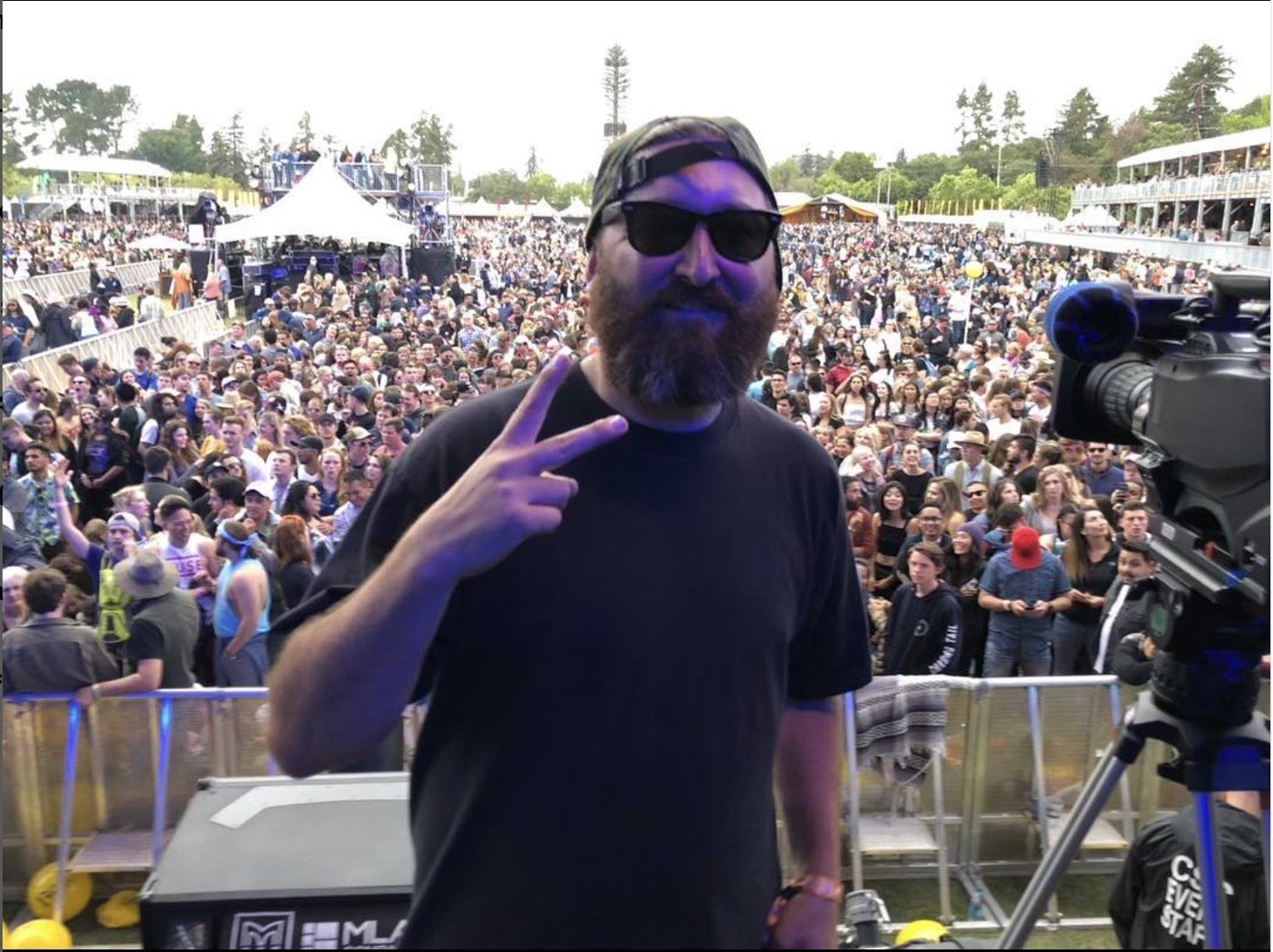 Daniel on stage next to a broadcast camera with the festival crowd behind him at BottleRock Napa Valley